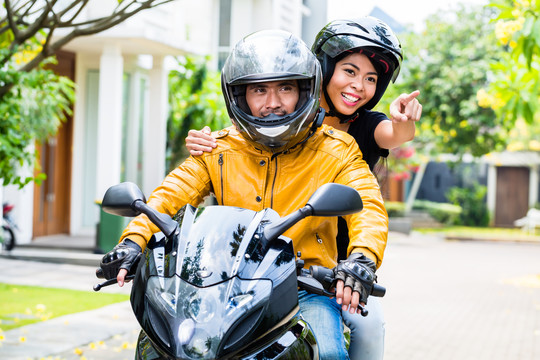一对戴着头盔的夫妇骑着摩托车，妻子坐在丈夫后面