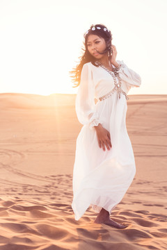 美丽的女孩站在沙漠的夕阳下