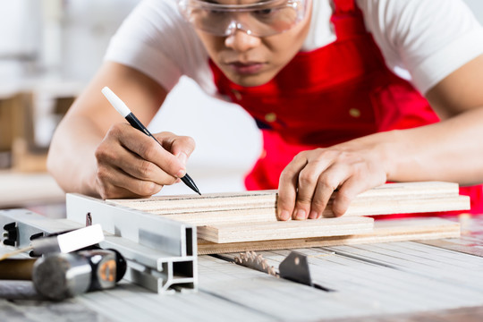亚裔中国木匠在他的工作室里用圆锯切割木材