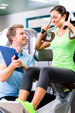 女私人教练在健身房做运动和健身，他向她展示训练计划