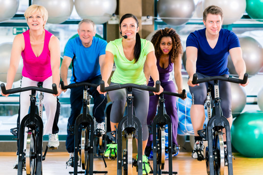 健身组的男性和女性在健身房旋转自行车，以获得力量和健身