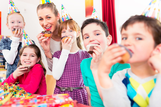 孩子们和所有的朋友和妈妈一起在大型聚会上吃纸杯蛋糕庆祝生日