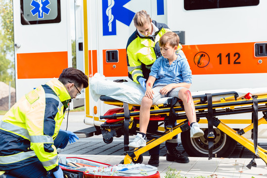 急救医生照料坐在担架上的事故遇难男孩
