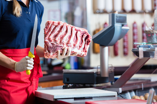 一位女屠夫在她的店里用刀切一塊肋骨肉
