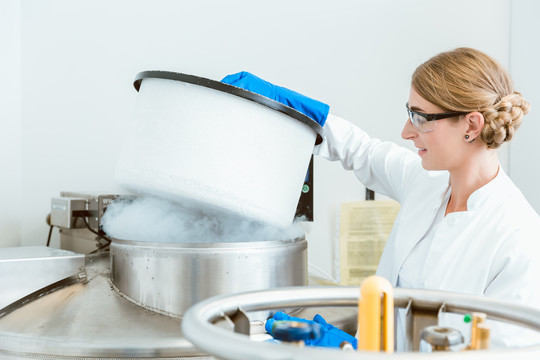 戴眼镜的年轻白种女性科学家的侧视图在实验室里提起机器的盖子