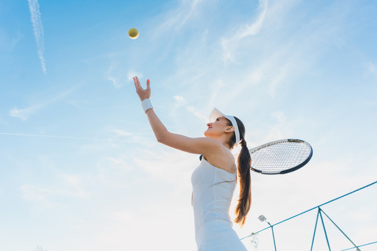打网球的女子发球向空中扔球