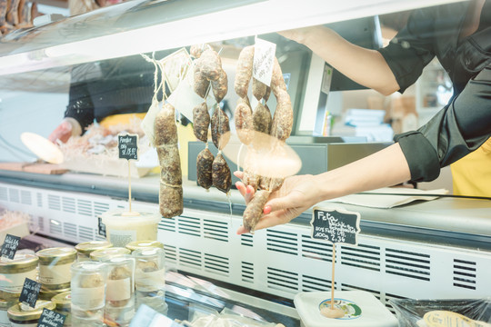 熟食店或超市的售货员在肉类柜台切割香肠
