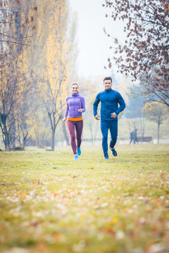 女人和男人在秋天公园的小路上跑步运动
