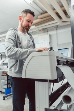 男子准备大幅面打印机在乙烯基上打印横幅
