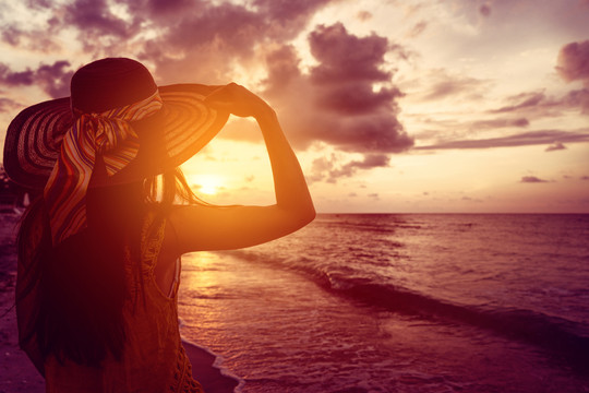 在热带海洋海滩看日落的女游客