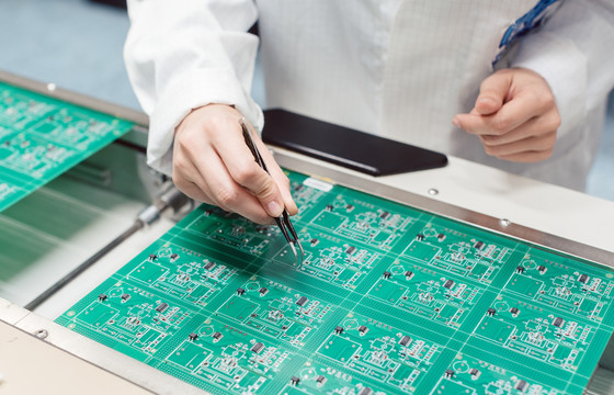 技术人员在生产线上通过将元件插入电路板来组装电子产品