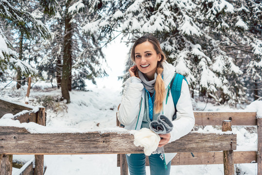 在冬天和下雪的徒步旅行中休息的女人看着相机