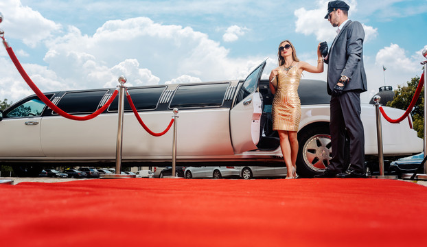司机在红地毯上帮助贵宾女士或明星下车参加招待会
