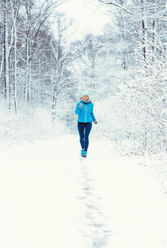 在寒冷多雪的森林里，一名女子慢跑着走向摄像机，以求健身