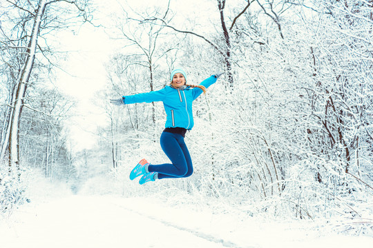 穿着运动服的开朗女人，享受着冬天和高高的跳雪