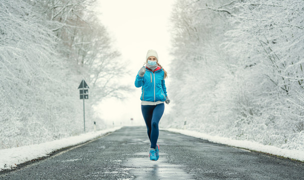 雪地景观中2019冠状病毒疾病的女性跑步或戴面罩慢跑