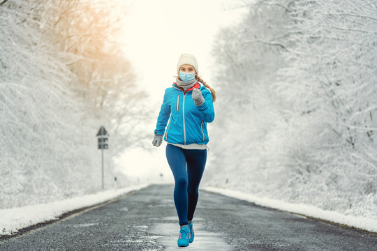 雪地景观中2019冠状病毒疾病的女性跑步或戴面罩慢跑