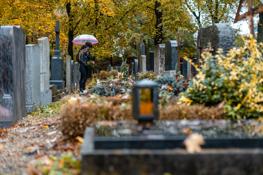 秋天墓地上的坟墓，一对夫妇站在坟墓之间哀悼死者