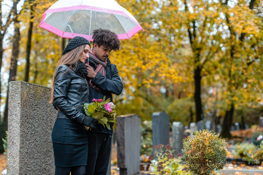 秋天下雨时，一对夫妇在墓地悲伤
