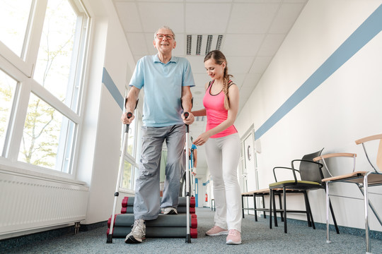 康复中心的老年人在受伤后学习如何拄着拐杖走路