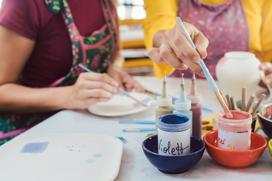 女人用刷子给手工制作的盘子上色