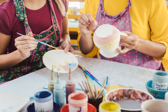DIY车间的妇女为自己的陶瓷盘子着色和装饰