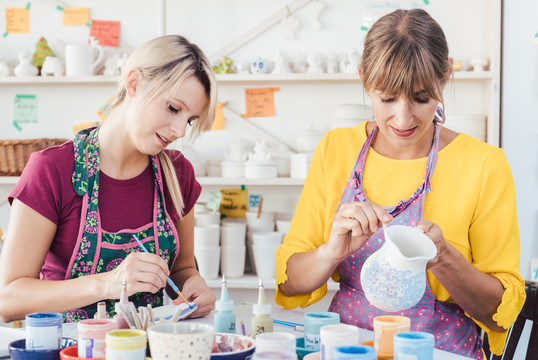两名妇女在DIY车间用刷子刷自己的陶瓷餐具