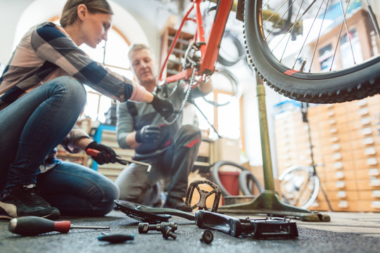 自行车修理工在自行车上工作，从地板上取工具