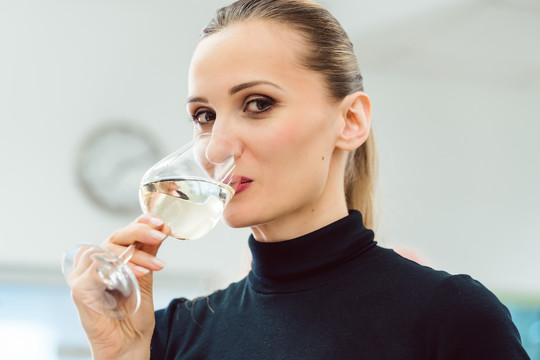 下班后喝一杯白葡萄酒的女人看着镜头