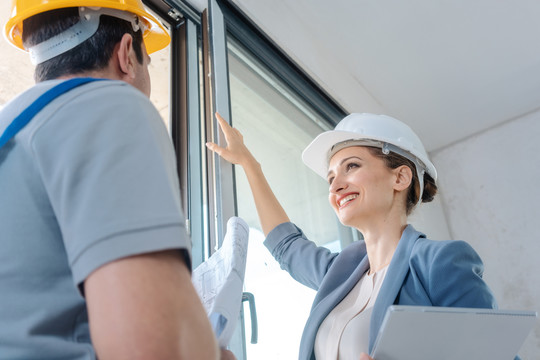 女建筑师和建筑工人在现场检查窗户