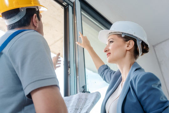 女建筑师和建筑工人在现场检查窗户