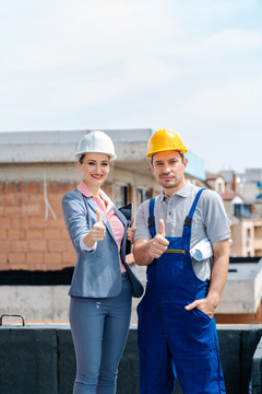 现场的建筑师和建筑工人竖起大拇指对着摄像机