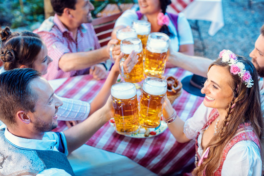 在阳光明媚的日子里，人们在巴伐利亚啤酒园享受美食和饮料