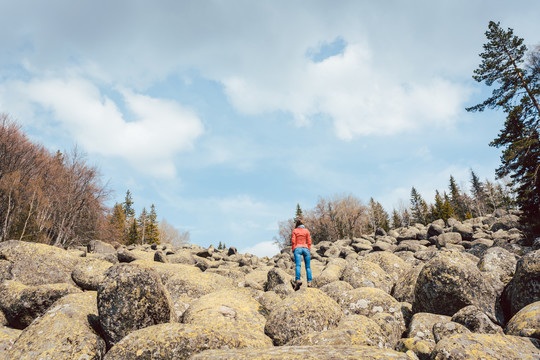 站在岩石上在野外徒步旅行的女人