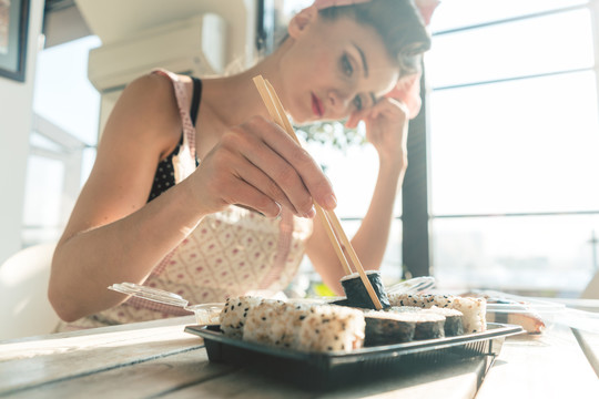 考虑到自己的生活，一位家庭主妇正在做家务休息，吃着寿司