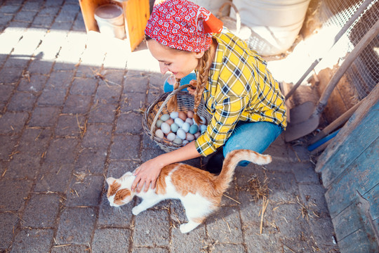 在农村的传统农场里，一位妇女抚摸着猫
