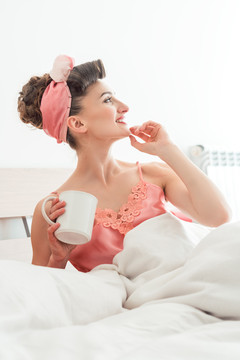 女人醒来时在床上喝着一杯咖啡，想着这一天会带来什么