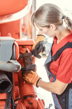 一名女机械师正在使用农场机器的扳手进行修理或维护