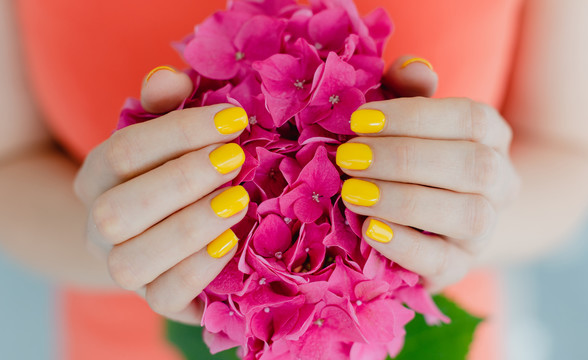手拿鲜花、指甲修剪成黄色的妇女