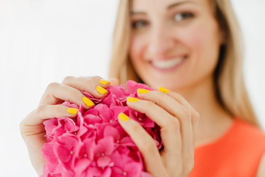 手拿鲜花、指甲修剪成黄色的妇女