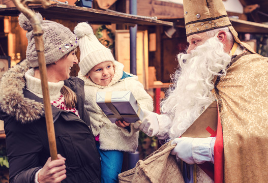 圣·尼古拉斯和他的员工在圣诞市场上见面，并向一家人赠送礼物