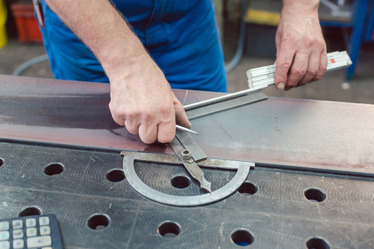 金属工人用折尺测量钢带以便以后切割