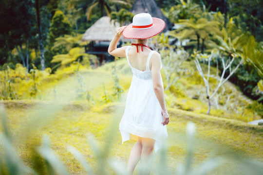 热带度假中的一位妇女手持太阳帽穿过丛林