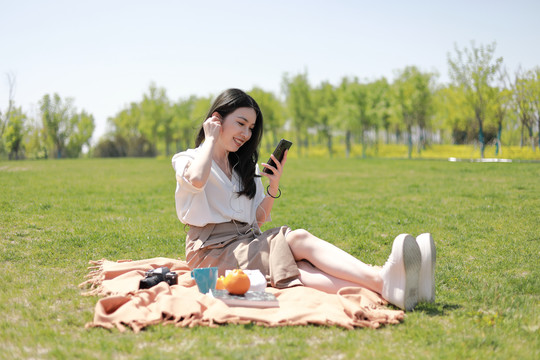 草坪上玩手机的美女