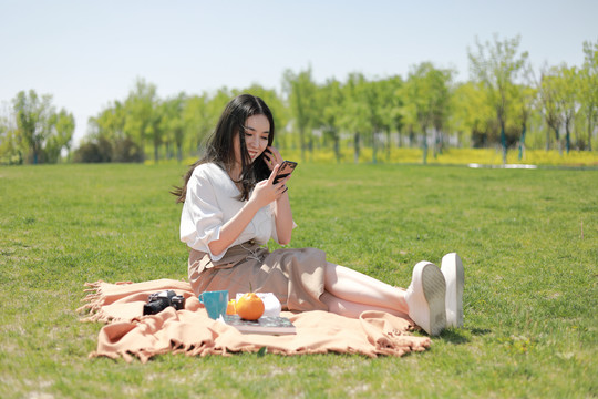 草坪上玩手机的美女