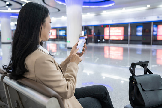 商务女士在机场坐着使用手机