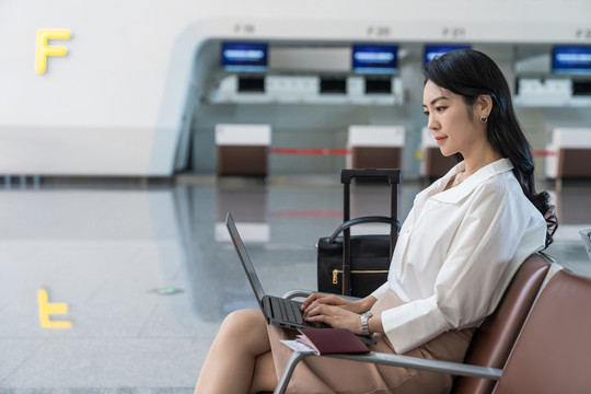 商务女士在机场使用笔记本电脑