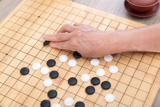 手拿围棋棋子在棋盘上落子