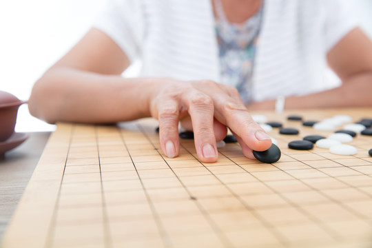 手拿黑色棋子在围棋棋盘上落子