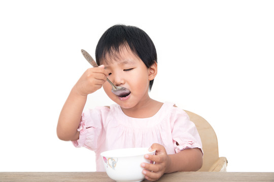 中国小女孩自己拿着勺子吃饭